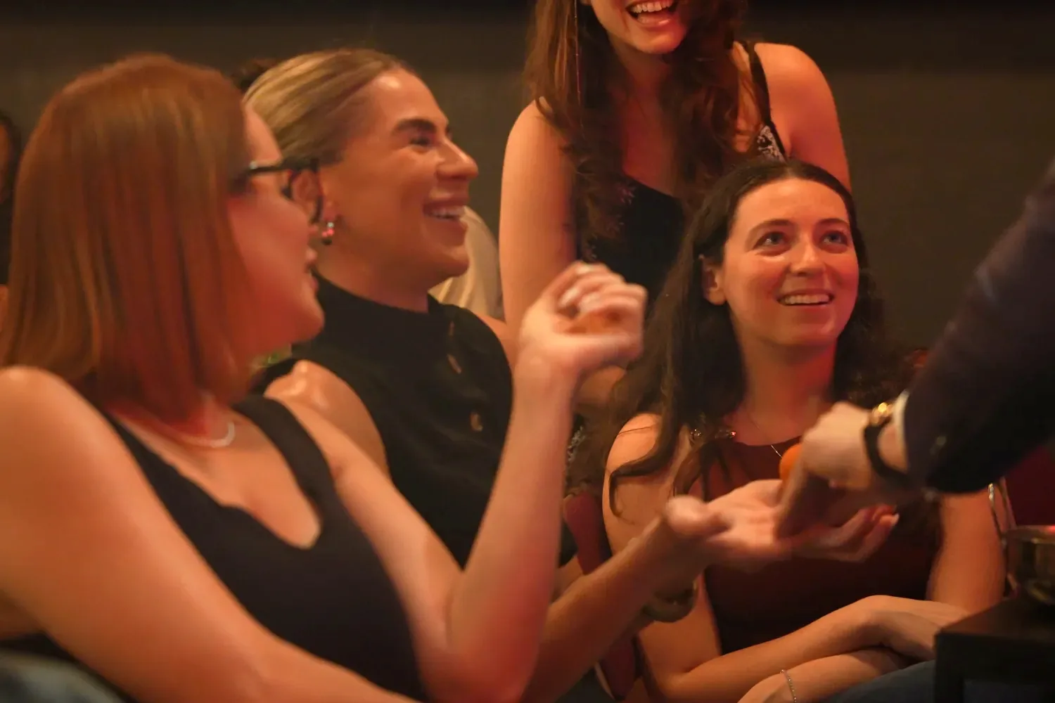Guests at a table laughing as a magician performs close-up